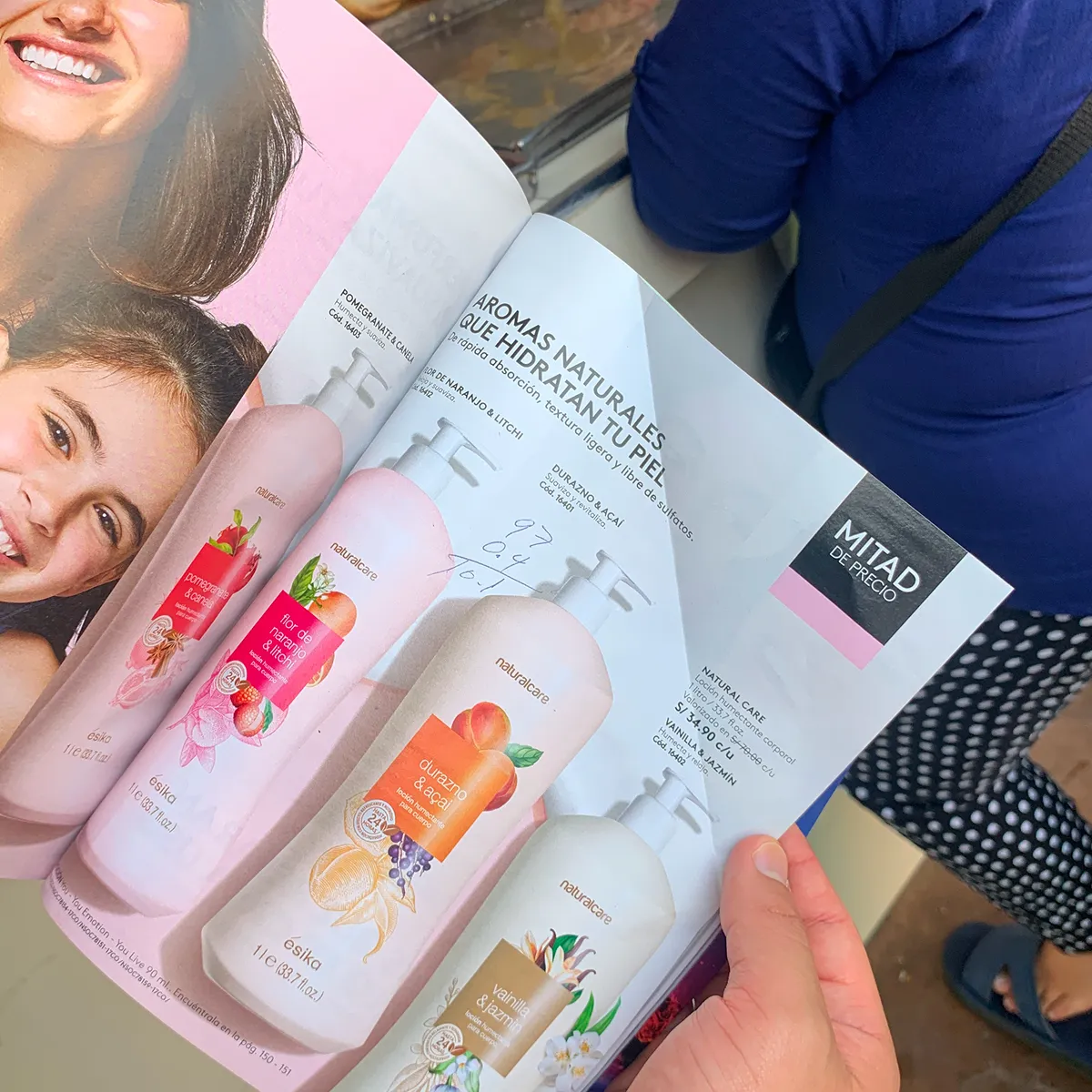 Catálogo impreso abierto en una página de lociones, con cantidades y precios anotados a mano sobre el papel